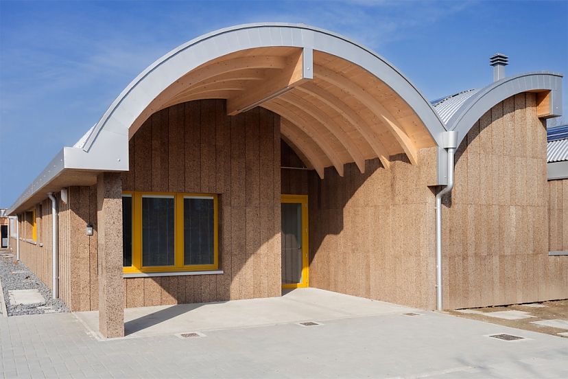 Fachada exterior de vivienda de corcho expandido liso color marrón con tejado de madera